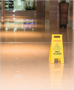 A caution wet floor sign sits in a hallway. Slip and falls are a common commercial general liability insurance claim.
