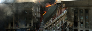 A destroyed building on fire, representing the need for terrorism risk insurance.