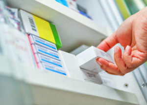 Closeup of a pharmacist's hand holding a medicine box.