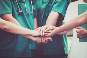 A group a doctors join hands together.