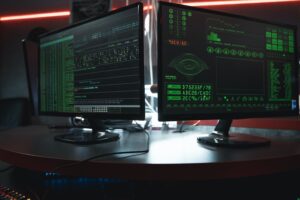 A close-up view of two monitors showing a system hack and ransomware activity.