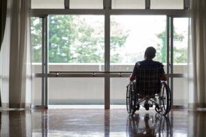 An older adult sits in a wheelchair, representing how hospitals simplify operations by selling post-acute businesses.