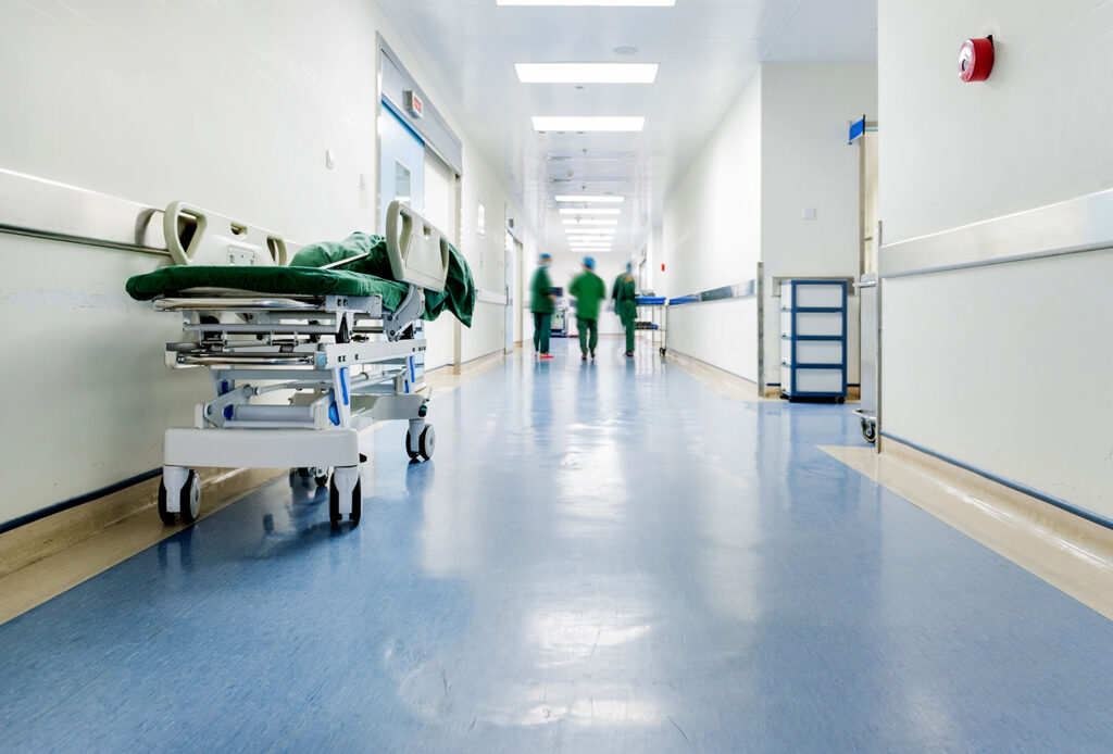 Medical staff walking in a hospital hallway, represents hospital merger activity.