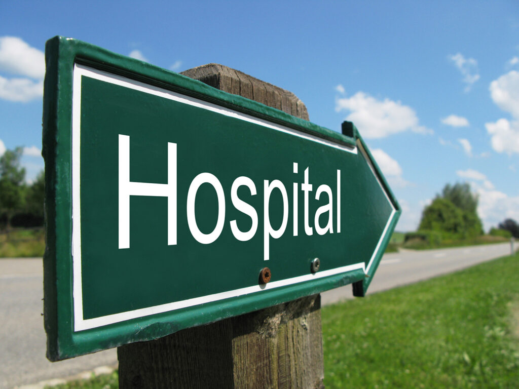 A hospital sign road in rural setting.