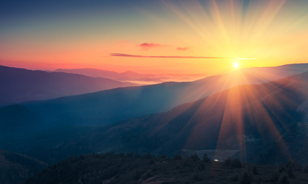 A sunrise over a mountain, represents the possible end of a hard market insurance cycle.
